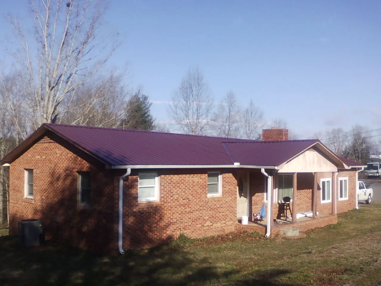Burgundy metal roof on a brick ranch home with a new addition in Ellsworth