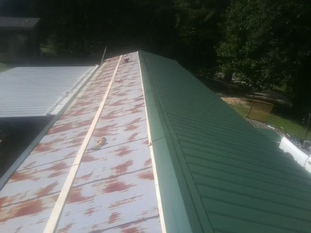 Old rusted panels beside newly installed green metal roofing — Wind Damage Roof Repair by Roofing Brothers in Ellsworth